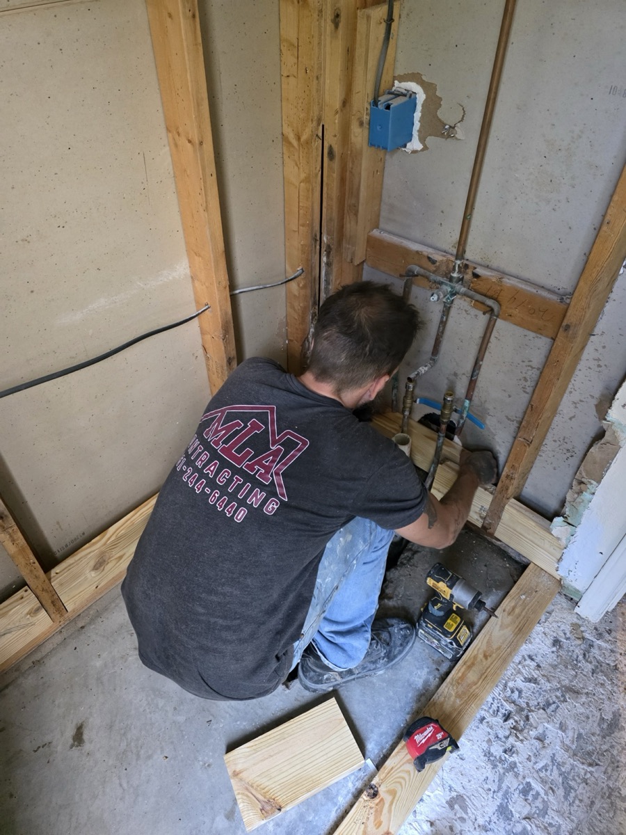 MLA Contracting crew member in a branded shirt roughing in plumbing