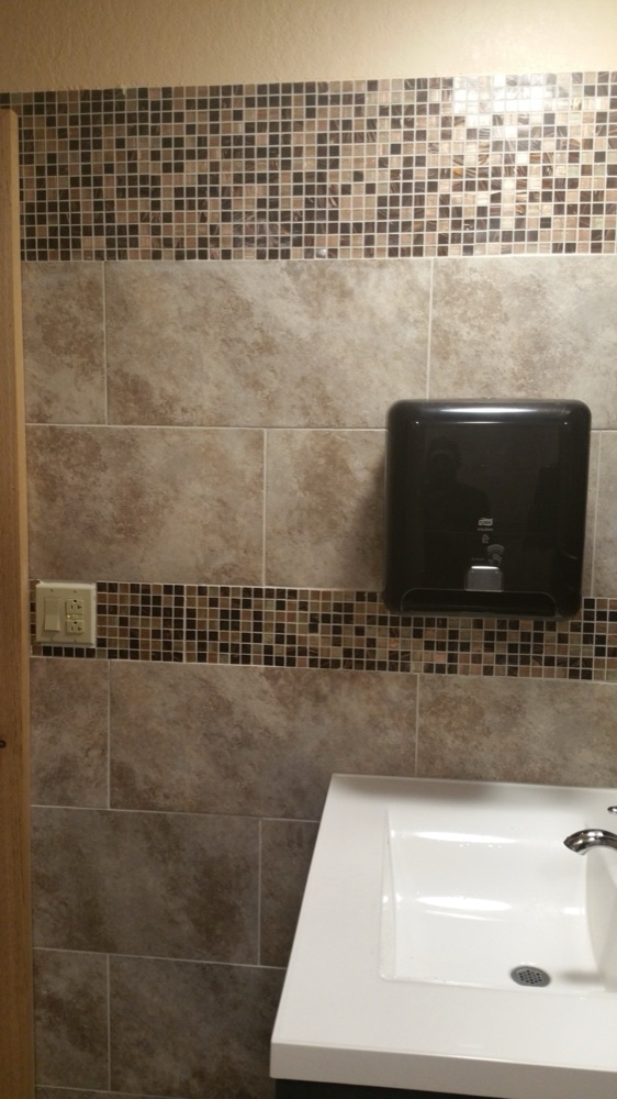 Commercial restroom with tile walls and mosaic band
