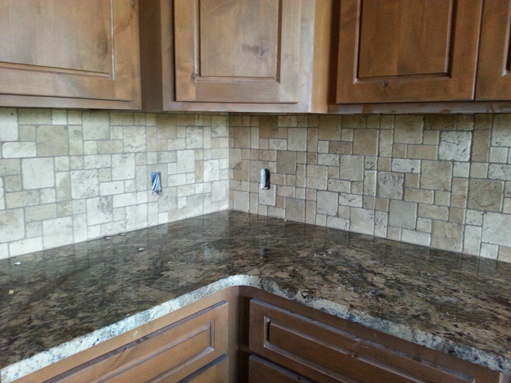 Remodeled kitchen with stone counters and travertine backsplash